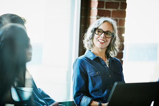 businesswoman-working-on-laptop-with-group